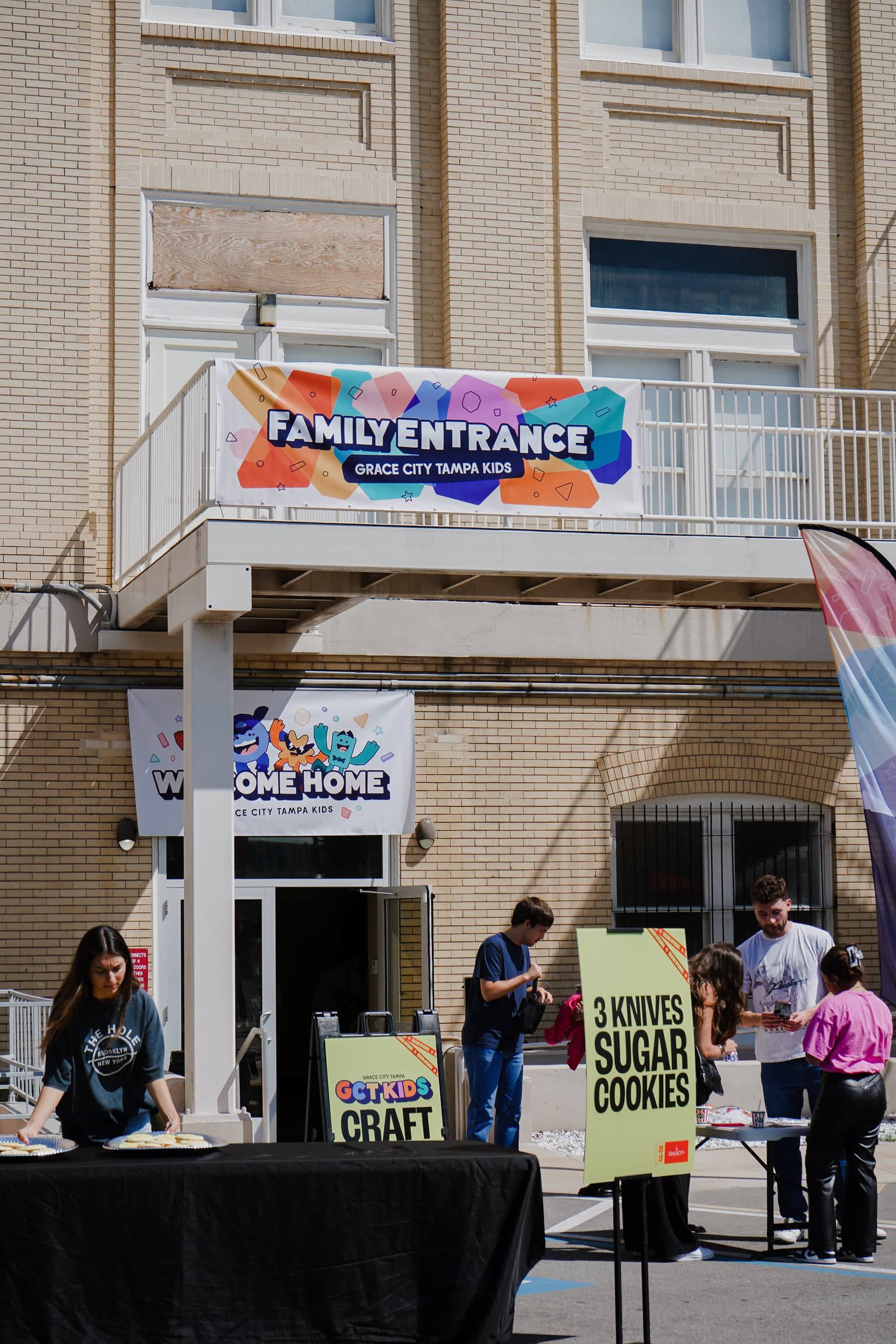 Families at an outdoor church gathering with welcome banners and activity signs